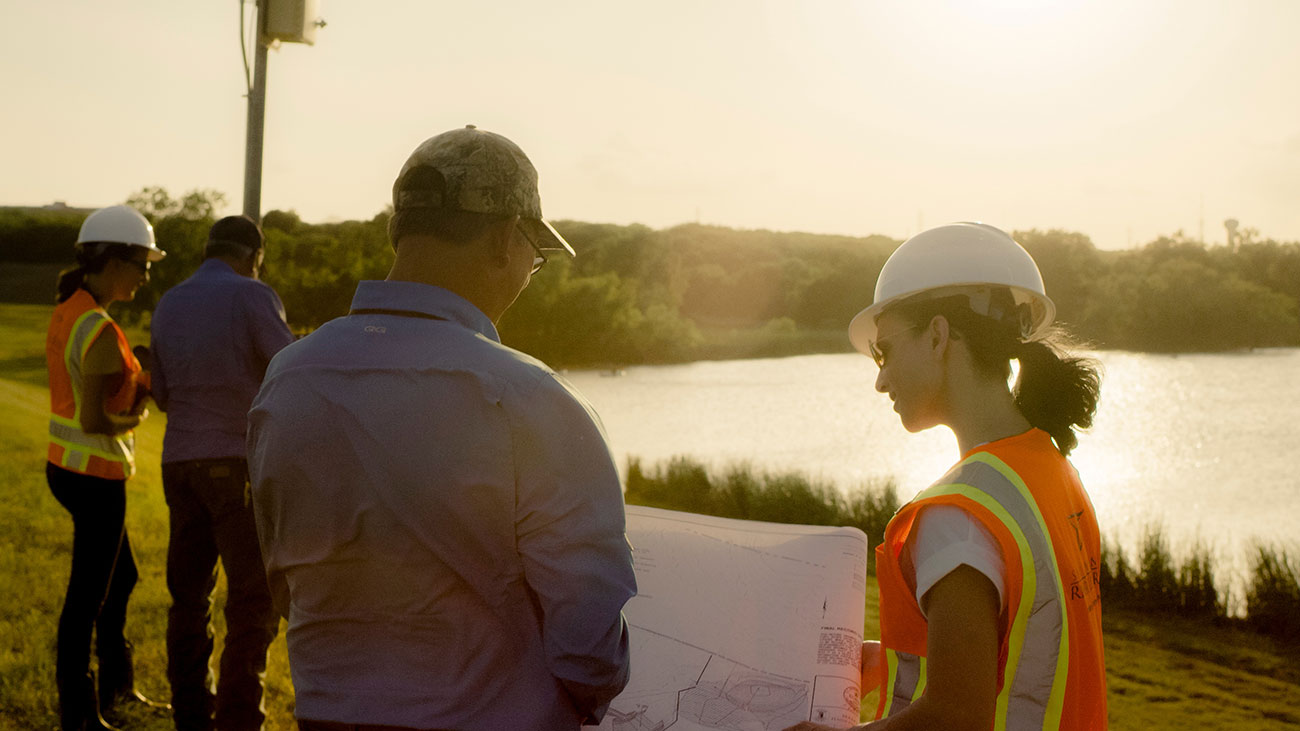 Two engineers reviewing a map near the river